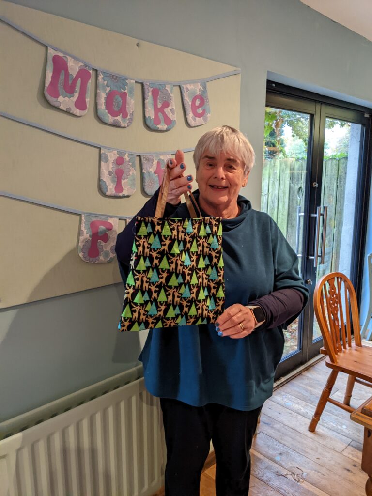 A woman with short white hair holding a bag she has made at one of our beginner's sewing classes