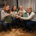 4 women smiling while sitting on a sofa with hand made gift bags and mugs